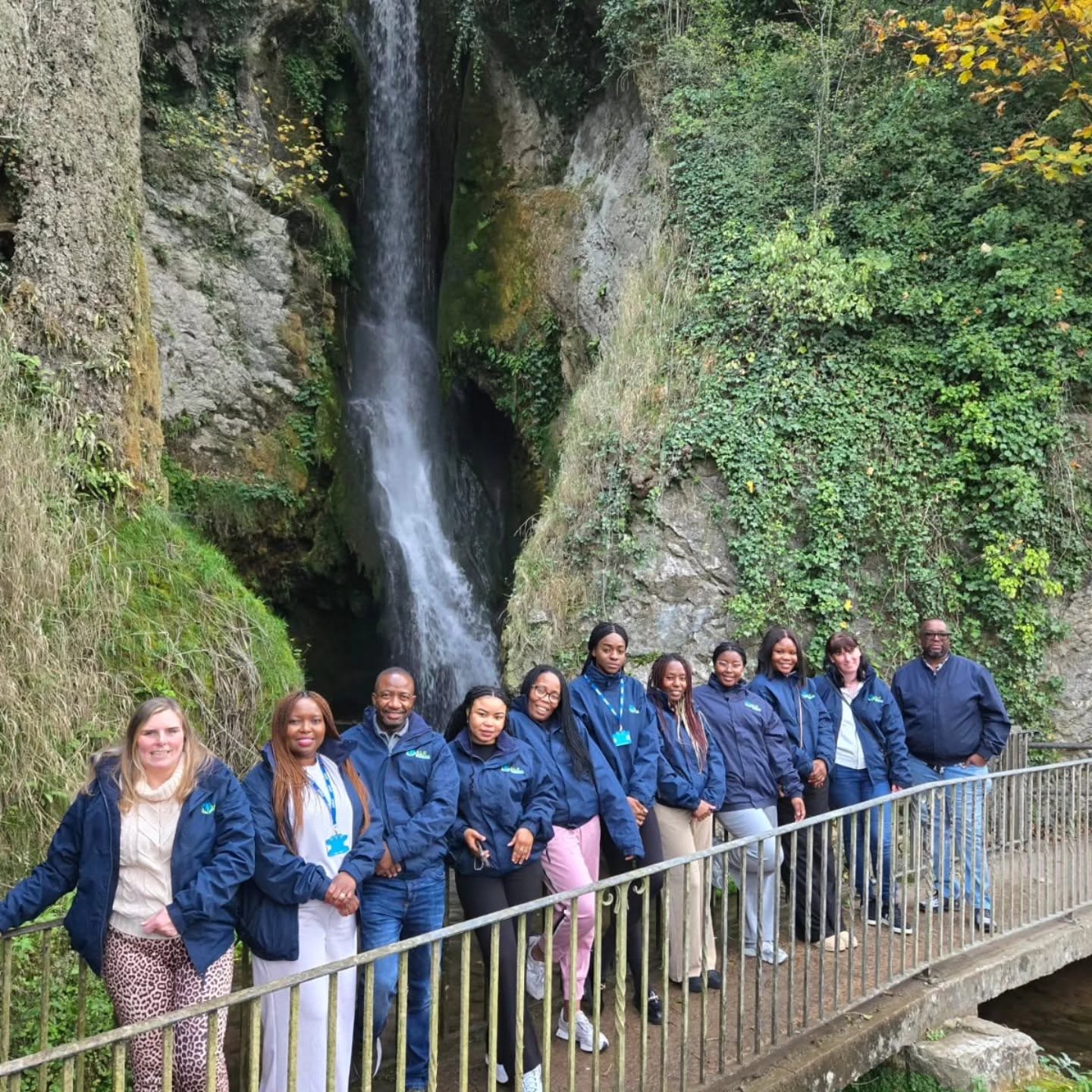 ALC team in matching jackets at a waterfall on the Leadership Away Weekend in North Wales